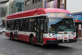 A red and white bus driving down a street