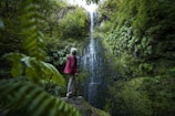 A man standing on a rock in front of a waterfall