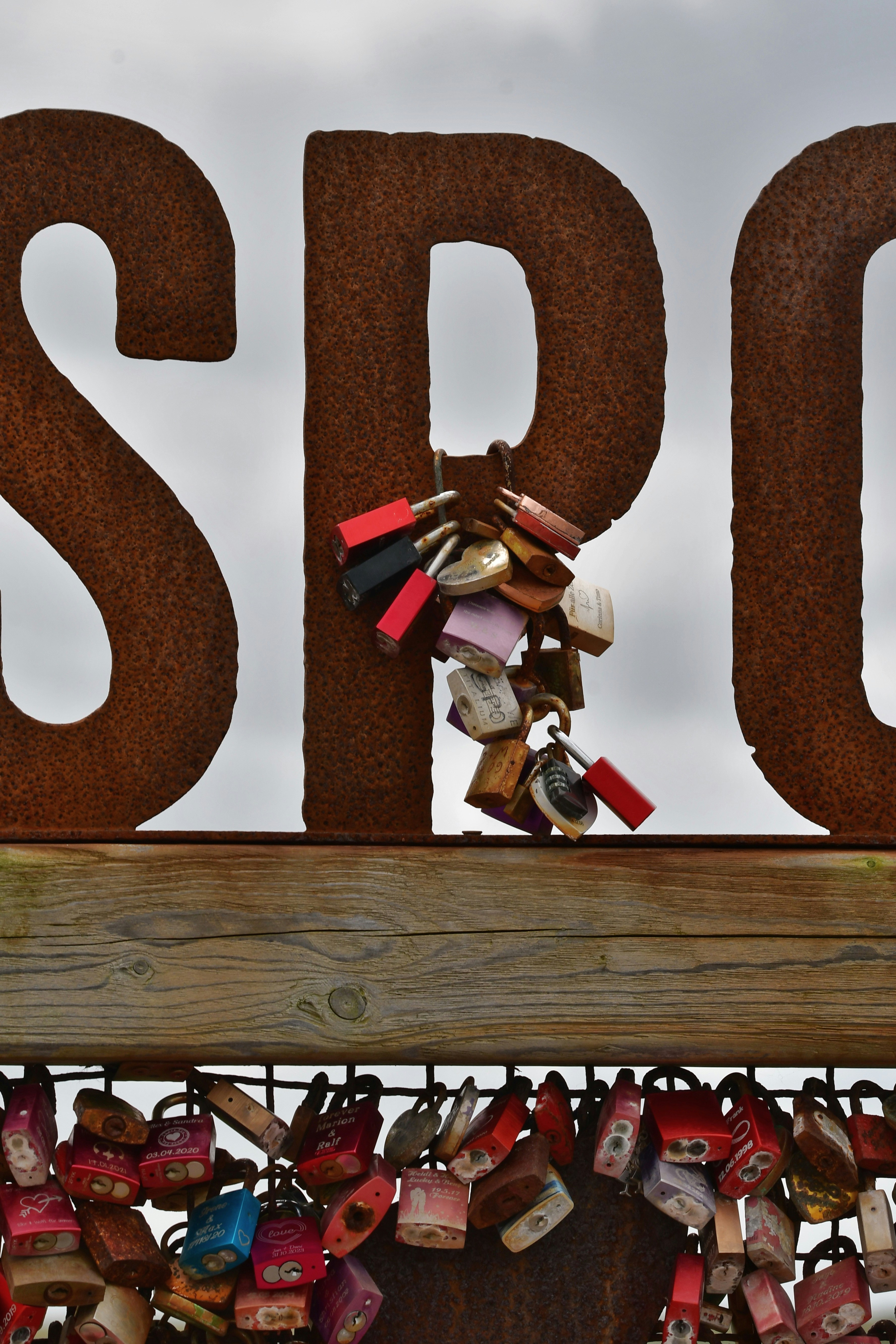 A wooden sign with a bunch of padlocks attached to it