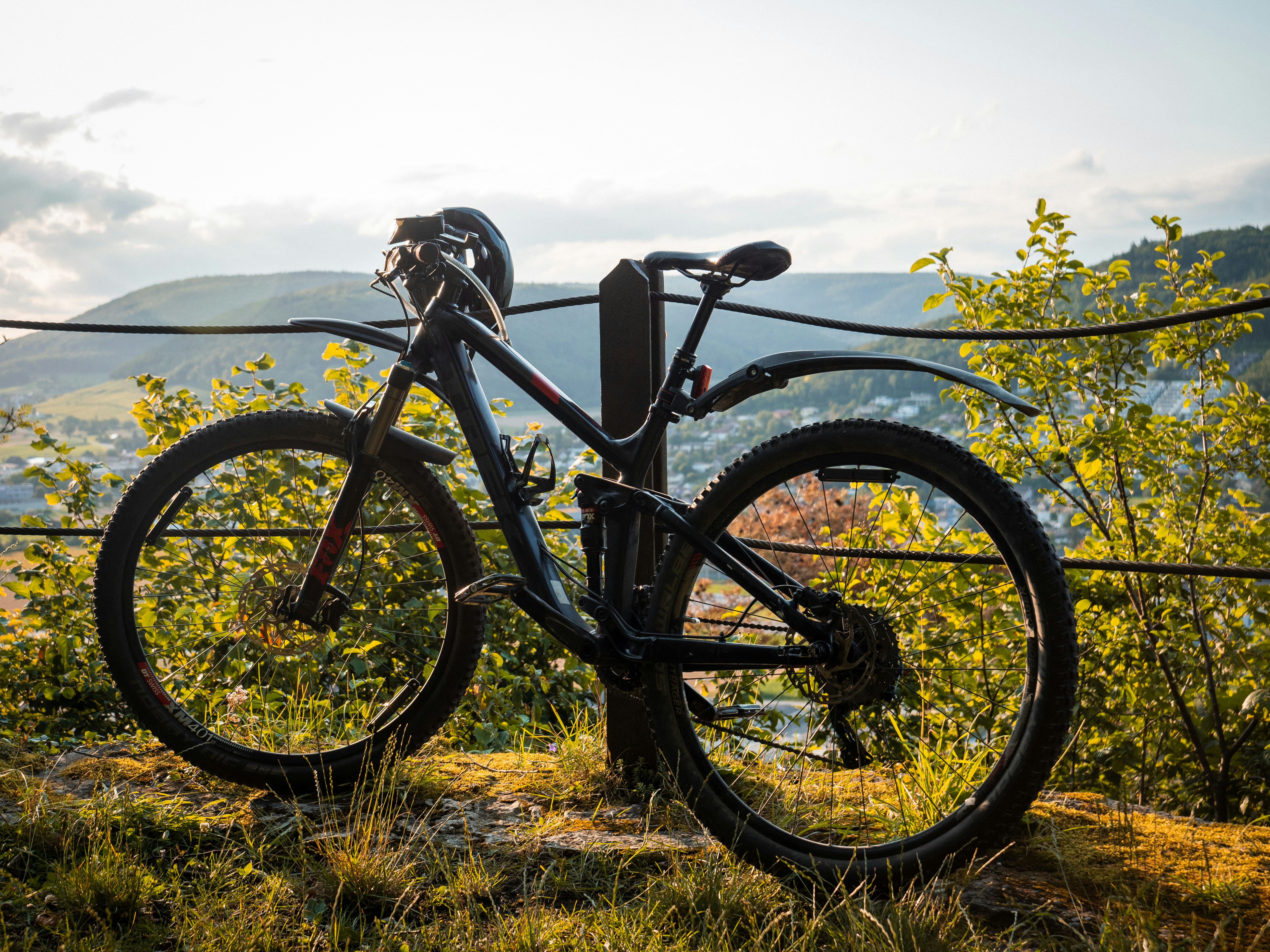 A bicycle is parked on the side of a barbed wire fence