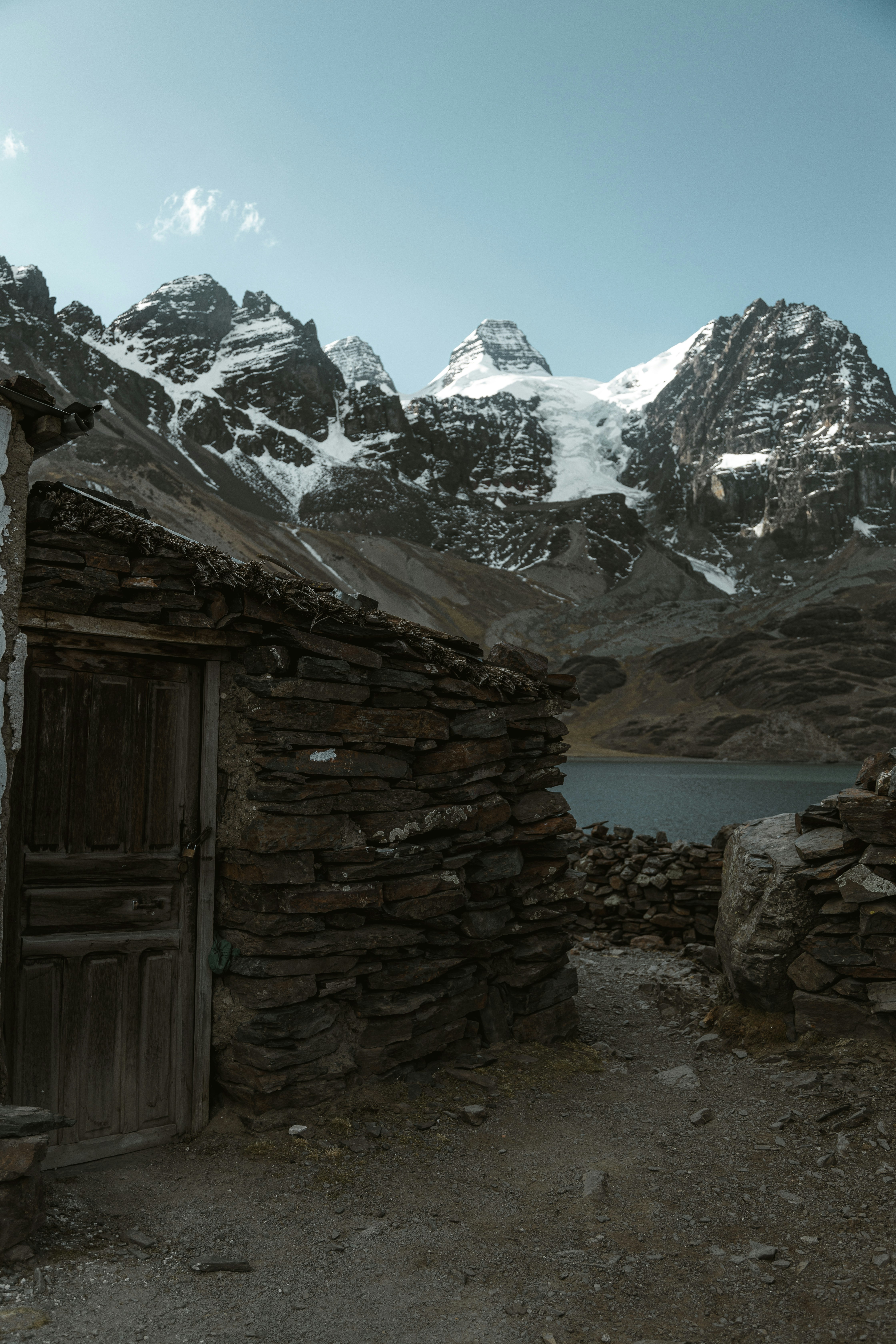 Un edificio in pietra con una porta di fronte a una catena montuosa