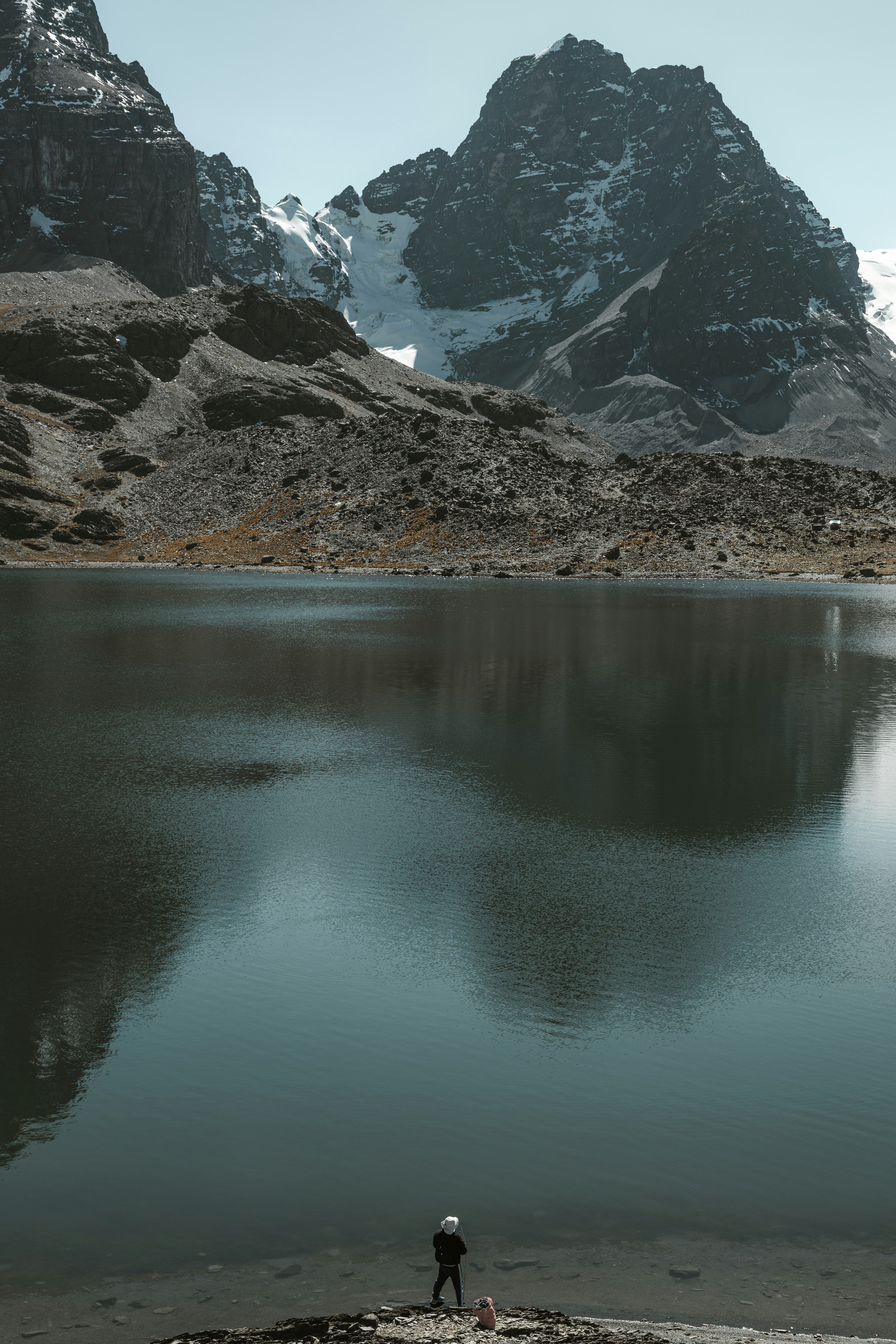 山々を背景に湖畔に立つ人物