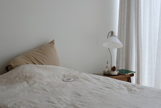A bed with a white comforter and a lamp