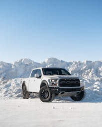 A white truck parked in front of a pile of snow