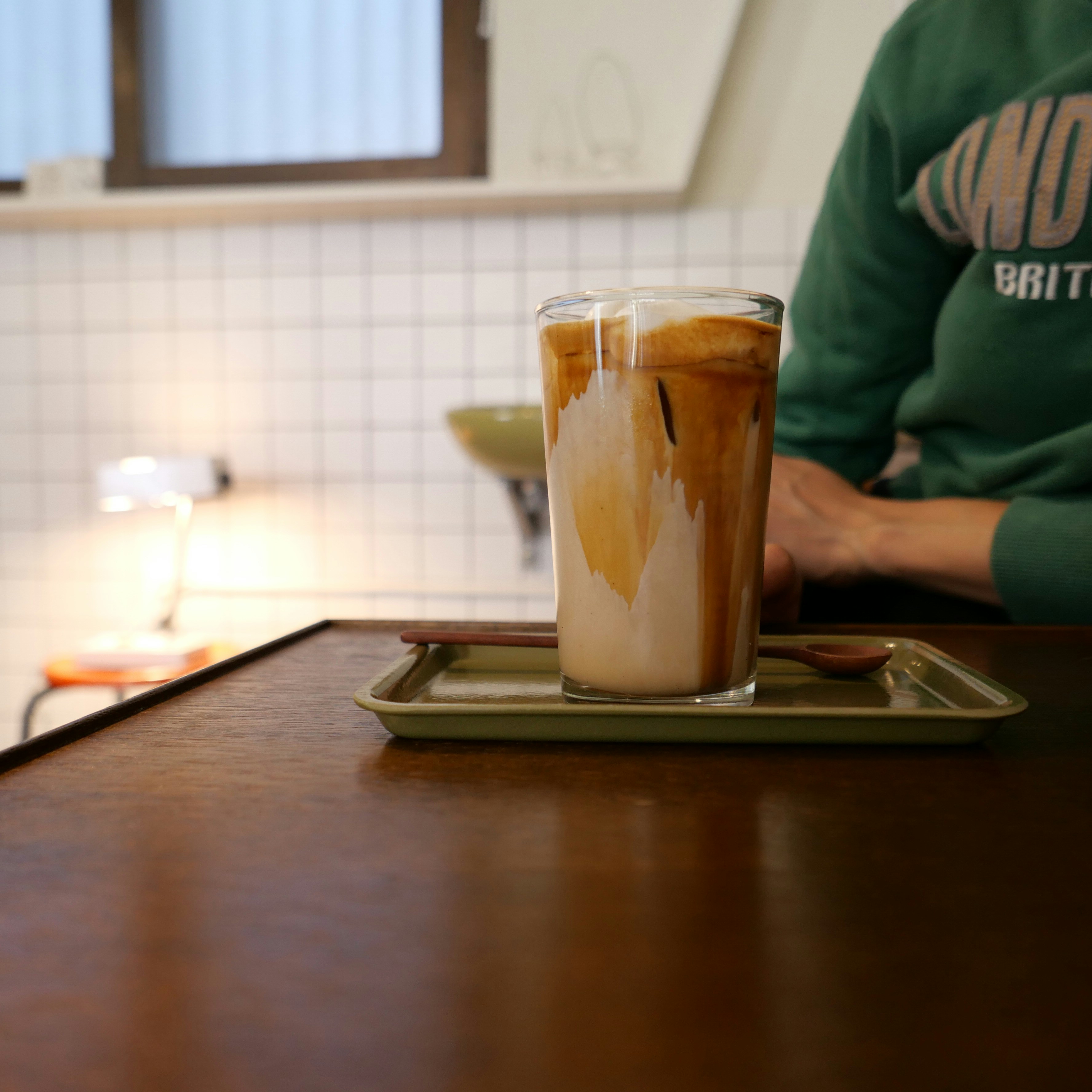 A person sitting at a table with a beverage in front of them