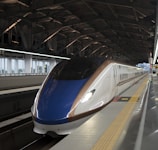 A blue and white train pulling into a train station