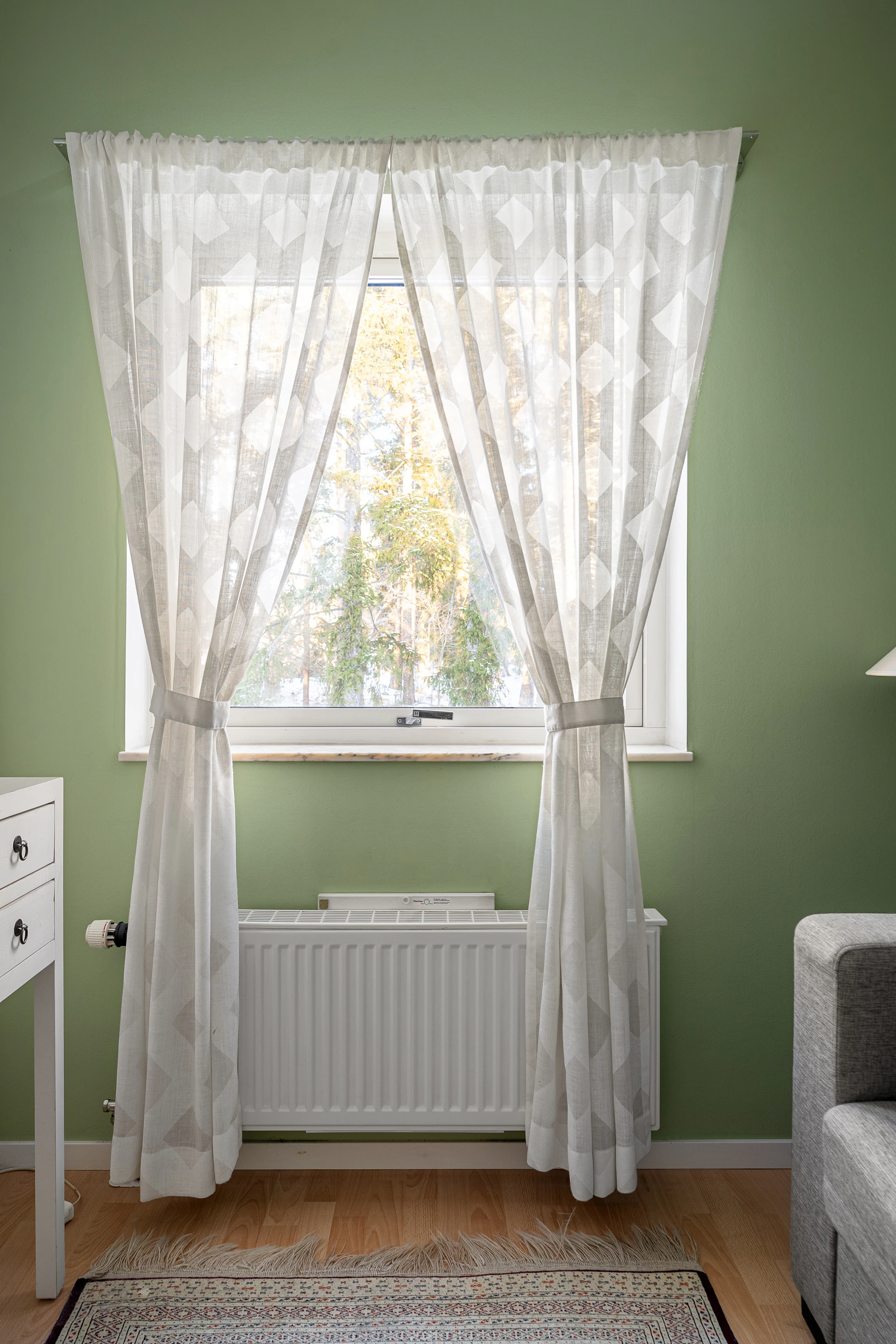 A living room with green walls and a white radiator