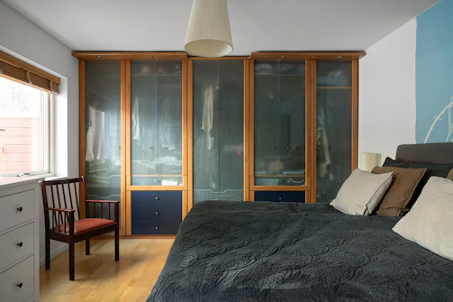 A bedroom with a bed, dresser and a chair