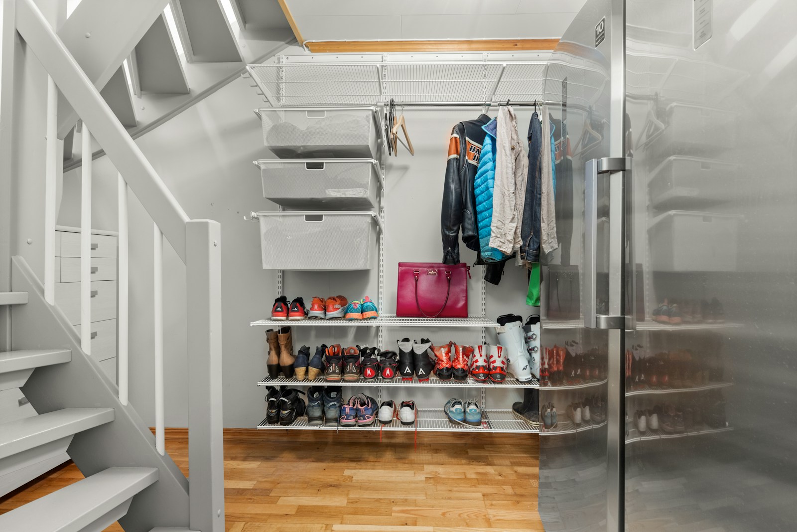apartment storage under stairs with white shelving shoes and coats
