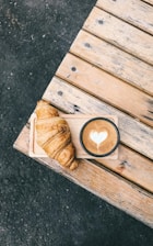 A cup of coffee and a croissant on a wooden table