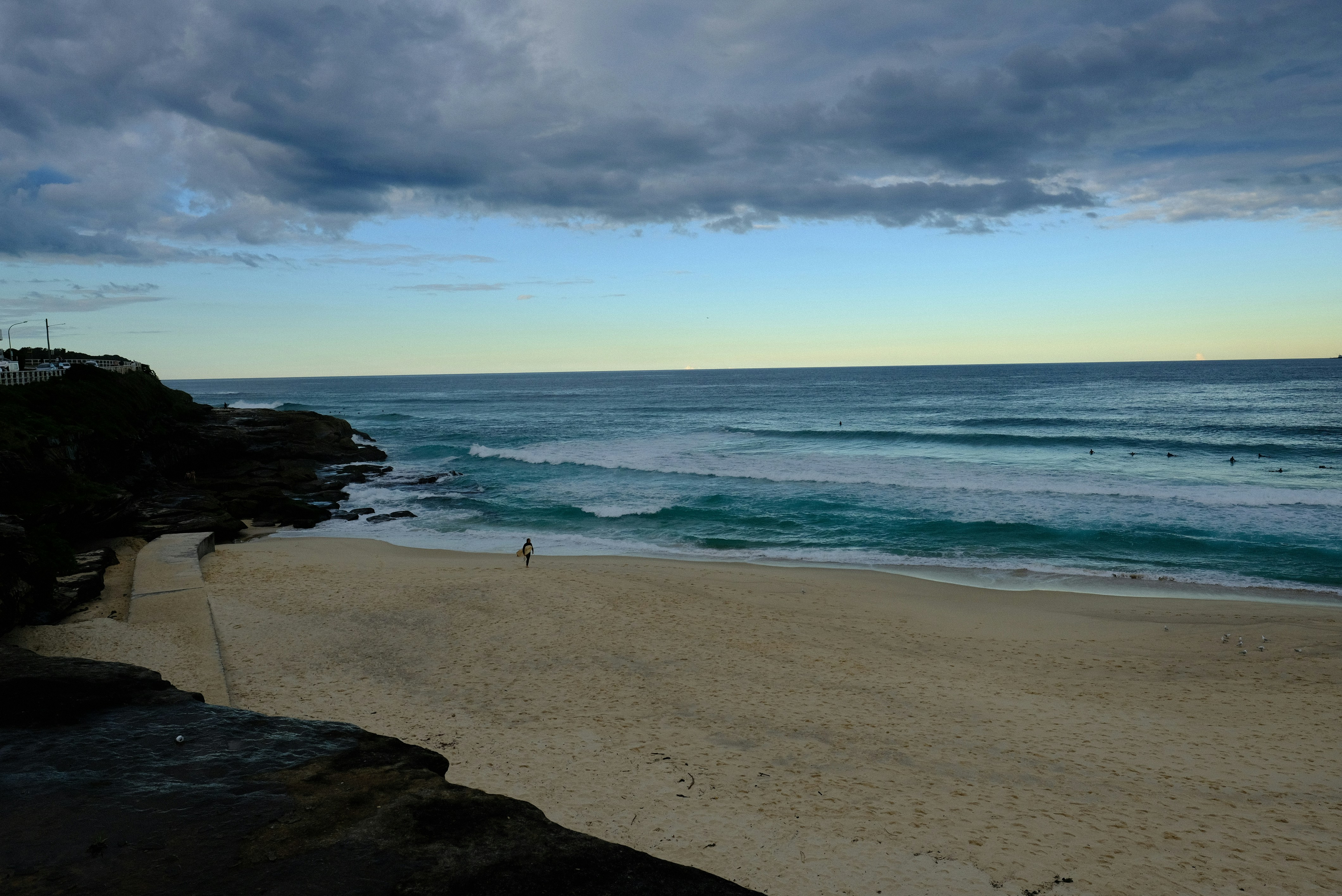 A long Northern Beaches sandbar with clean rolling lines stretching to the headland.