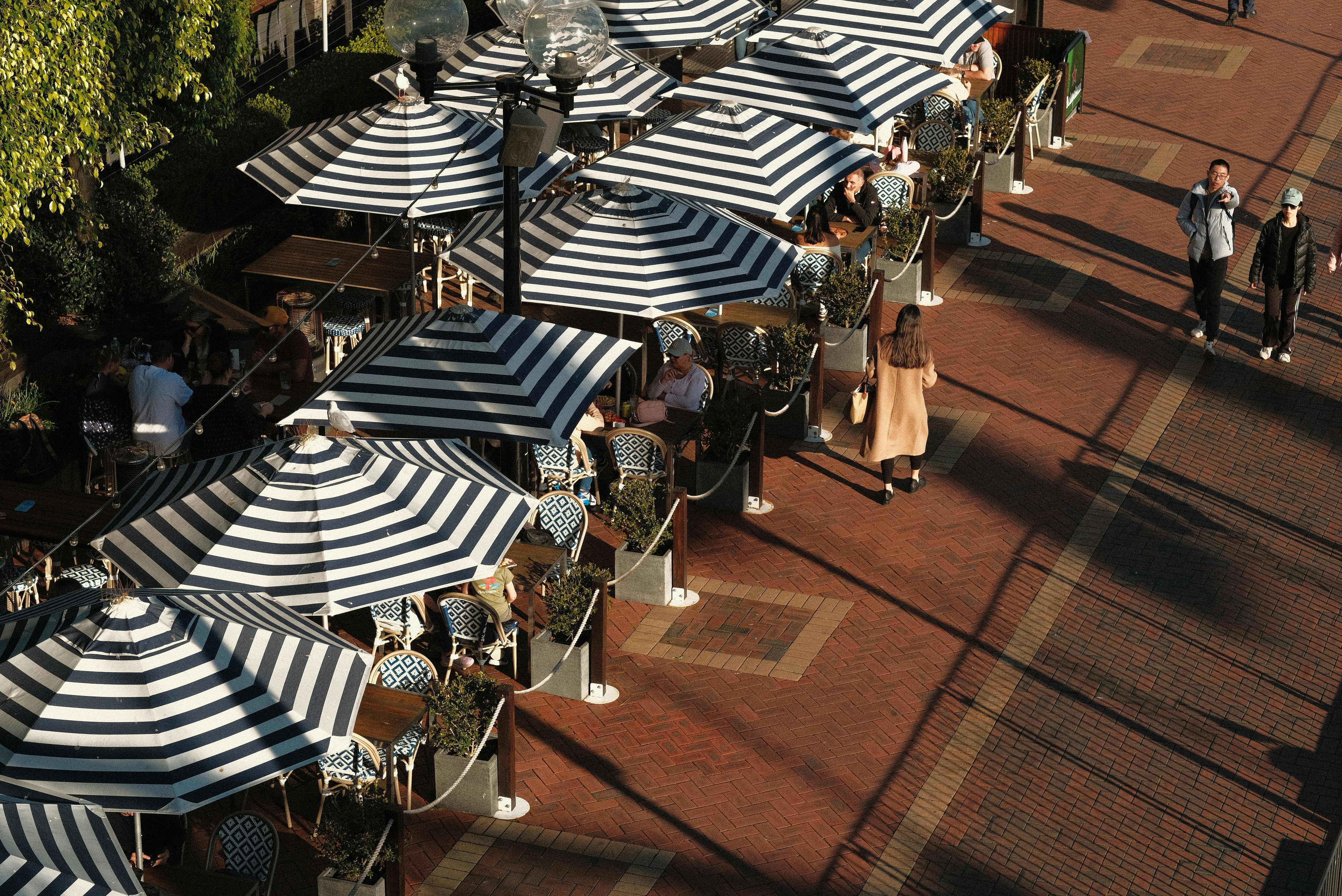 A group of people sitting under umbrellas on a sidewalk