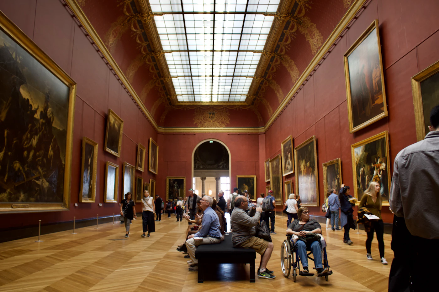 Bezoekers in een museumzaal vol schilderijen