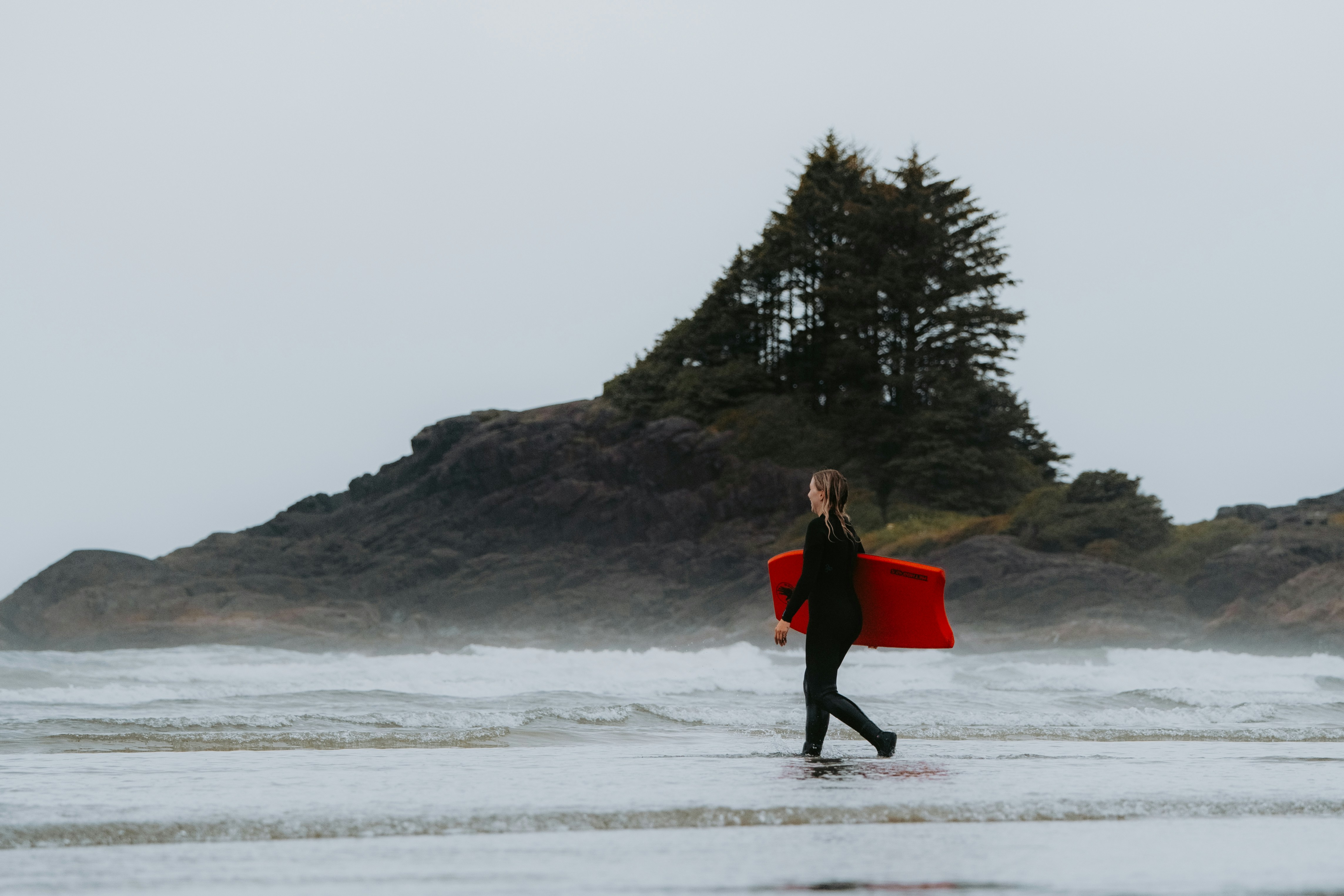 A person walking on a beach with a surfboard