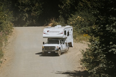 A truck pulling a trailer down a dirt road