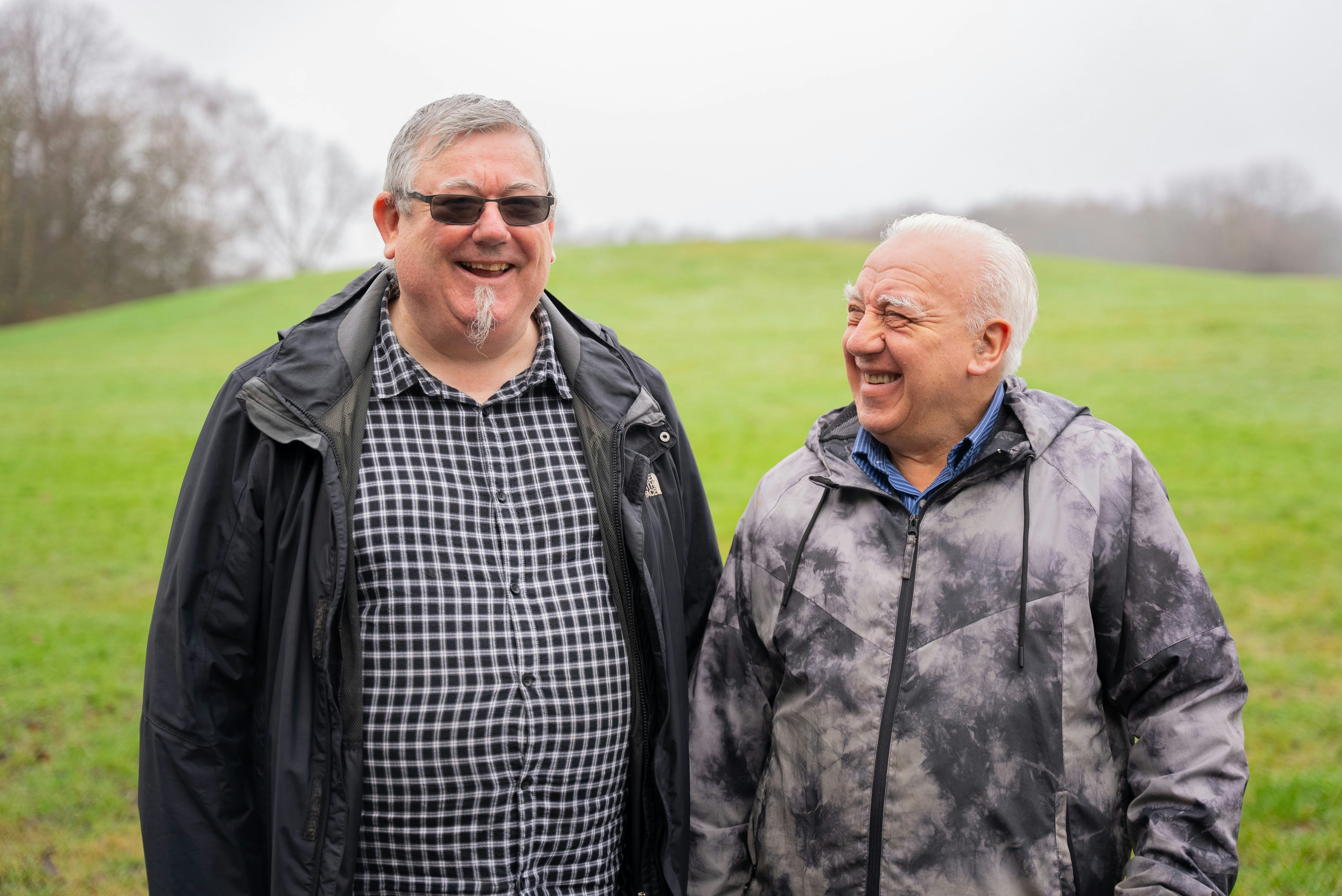 Two men standing next to each other in a field