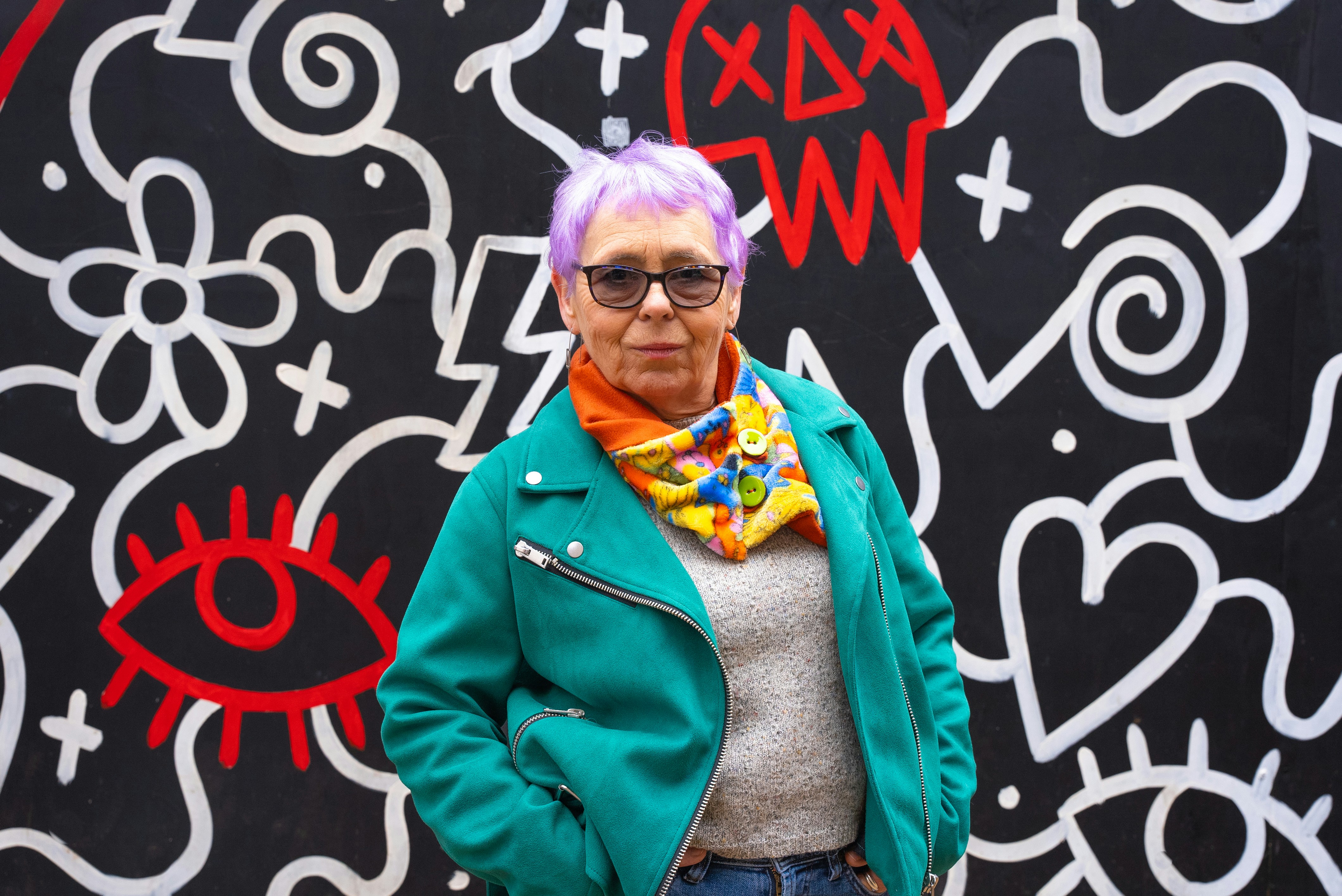 A woman standing in front of a graffiti wall