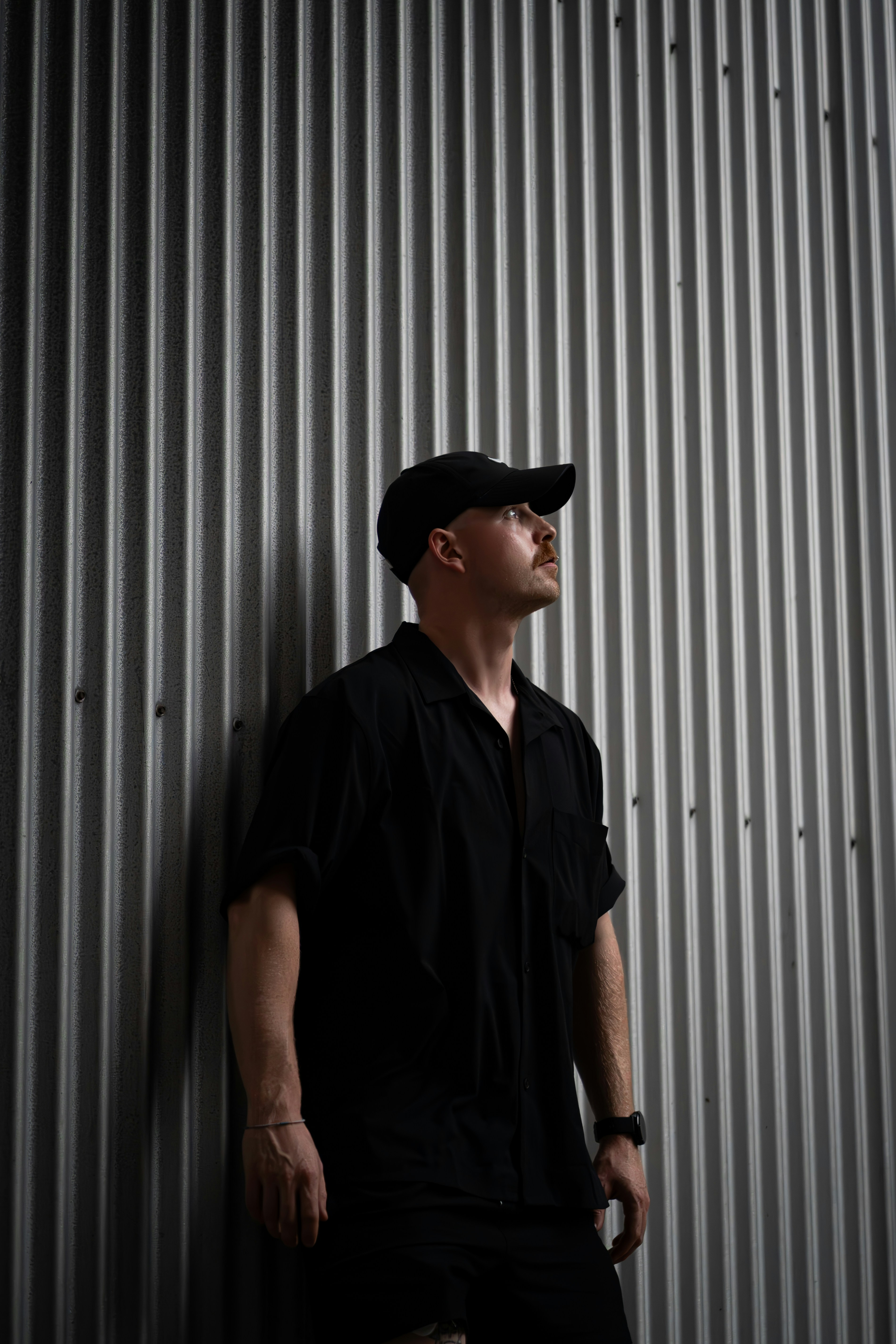 A man standing against a wall with his hands in his pockets