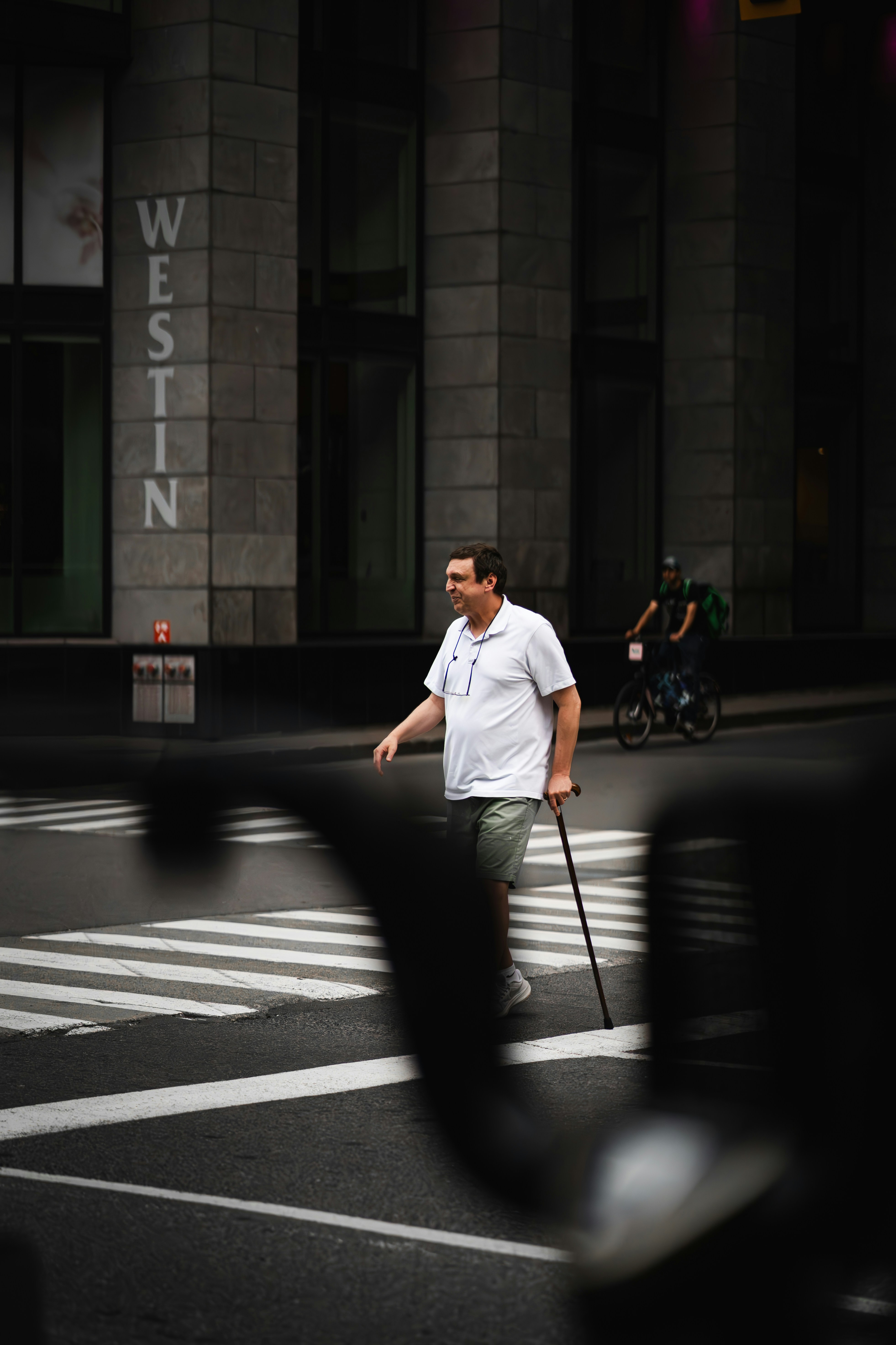 A man walking across a street holding a cane