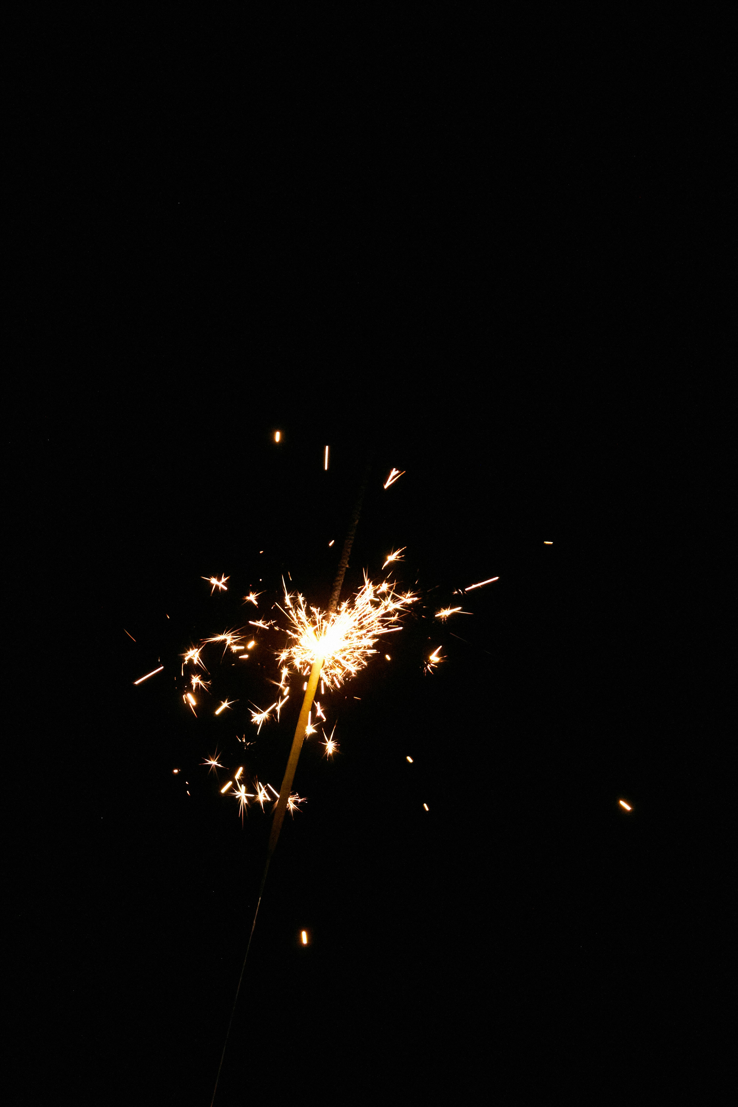A person holding a lit sparkler in their hand