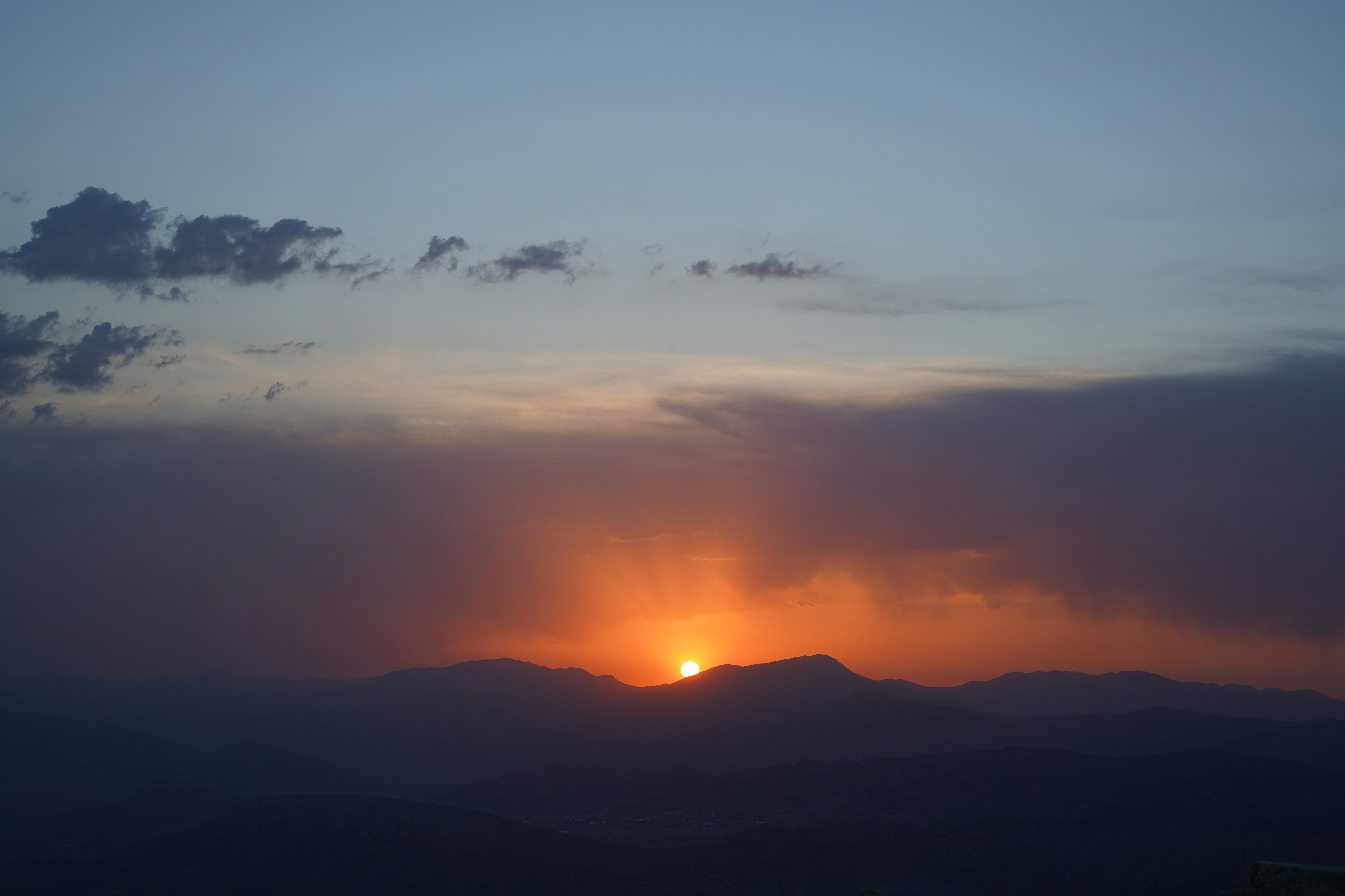 The sun is setting over a mountain range
