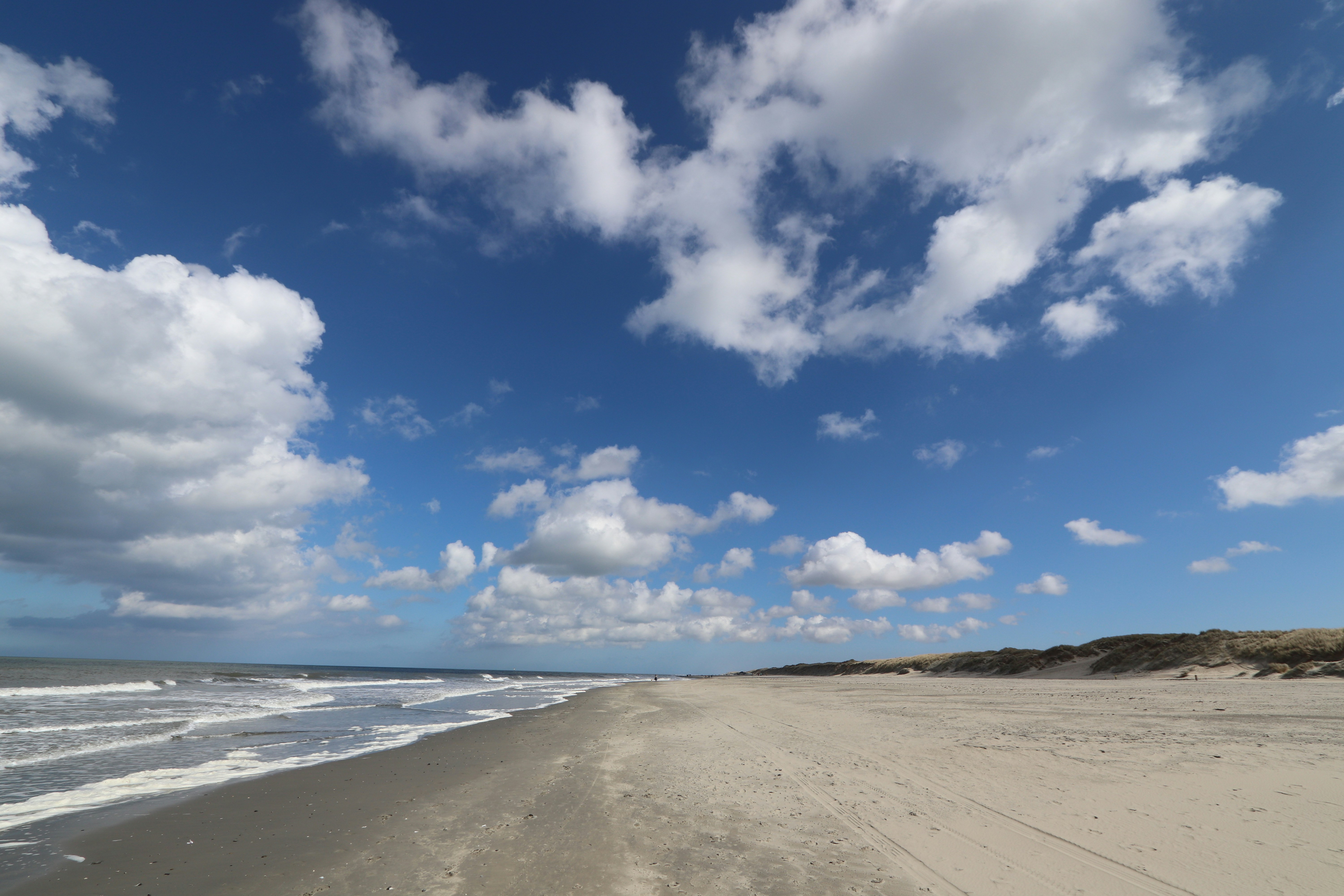 A sandy beach under a partly cloudy blue sky