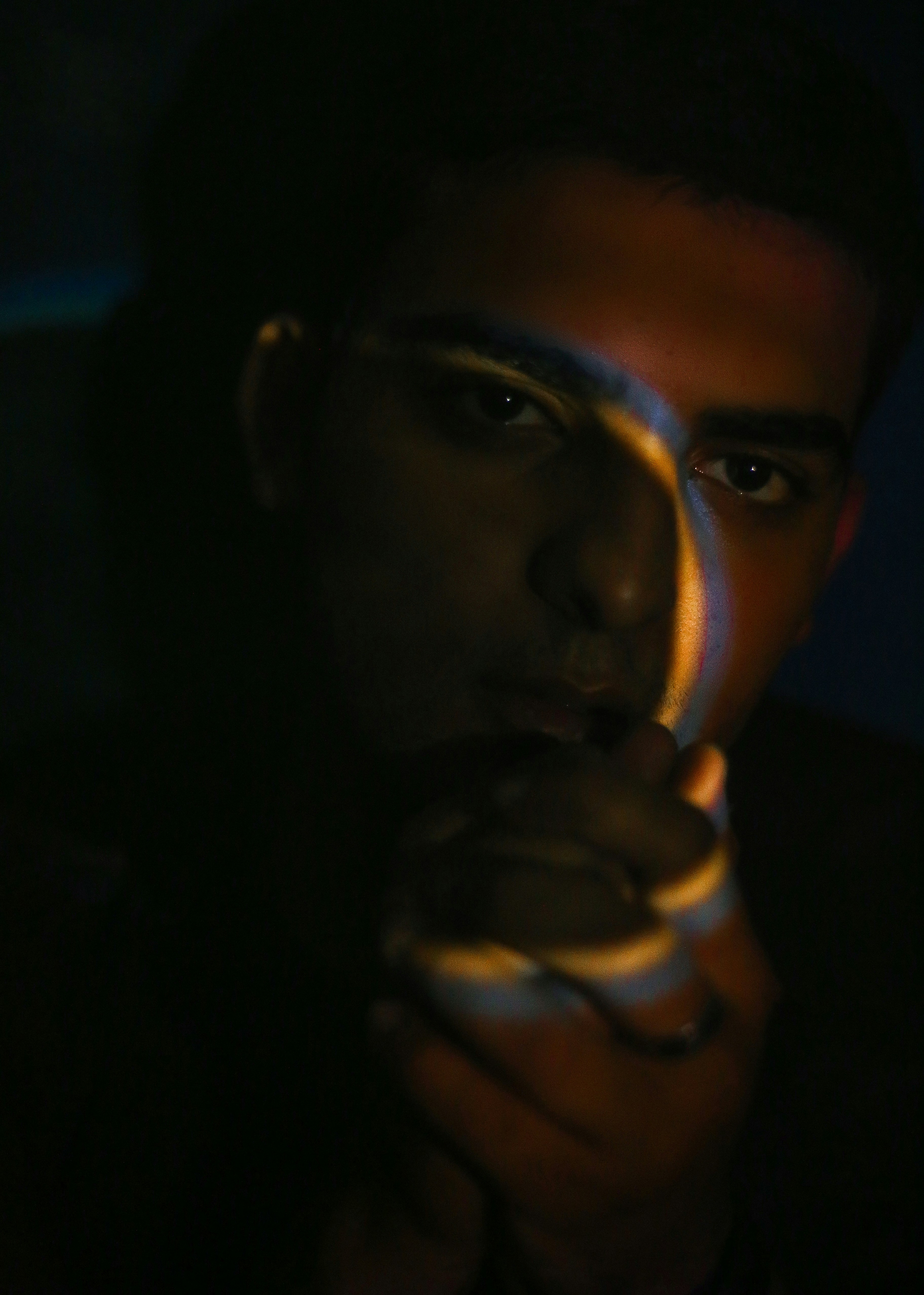 A man holding his hand to his face in the dark