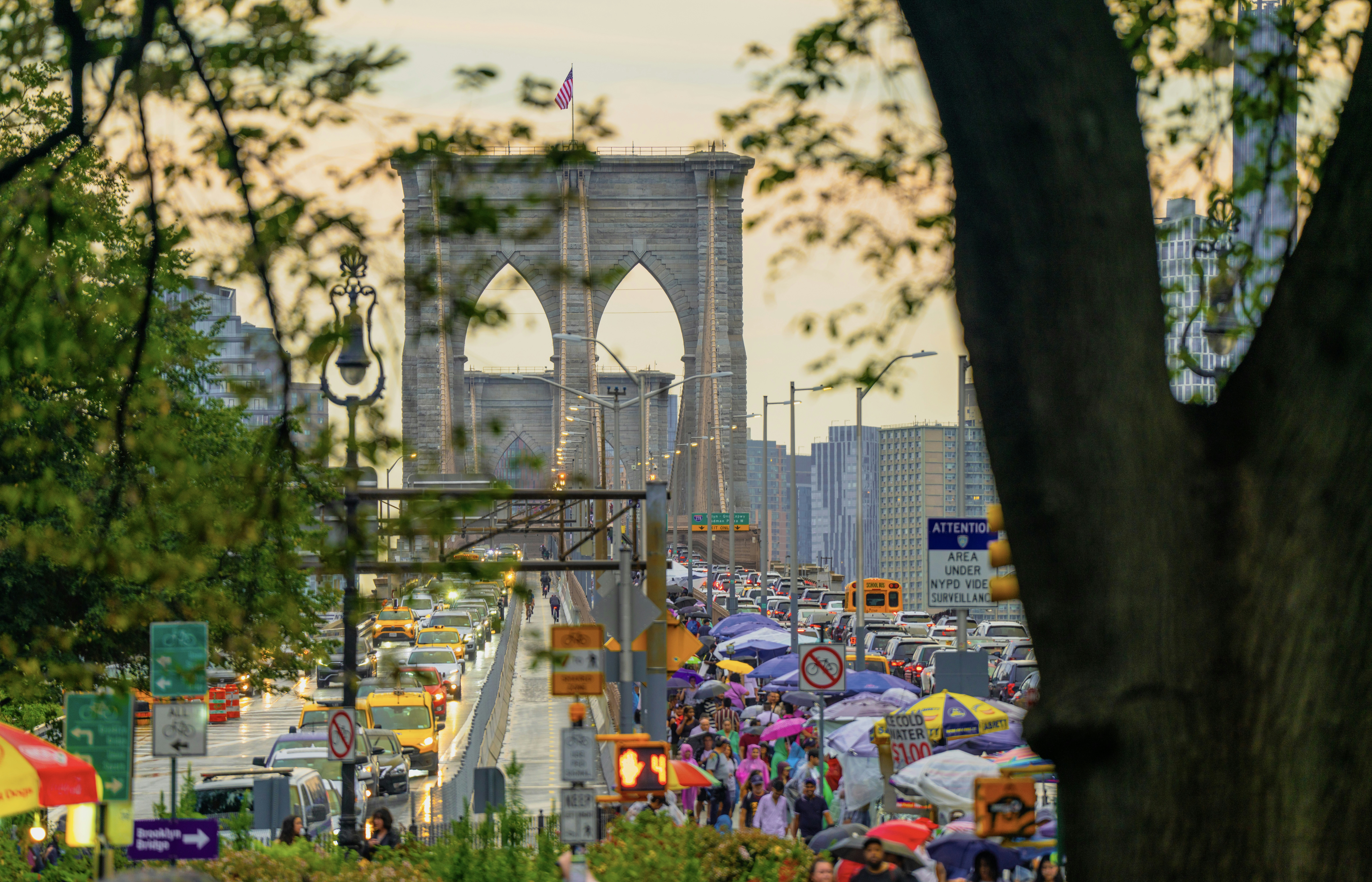 A crowd of people walking down a street next to a bridge