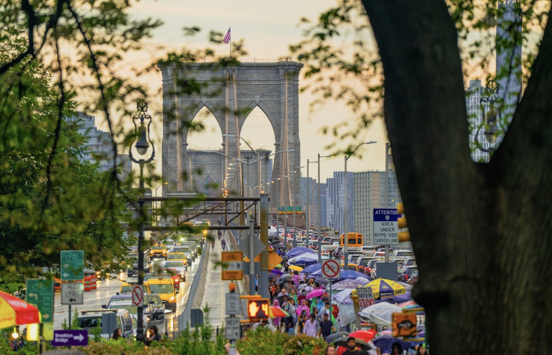 A crowd of people walking down a street next to a bridge