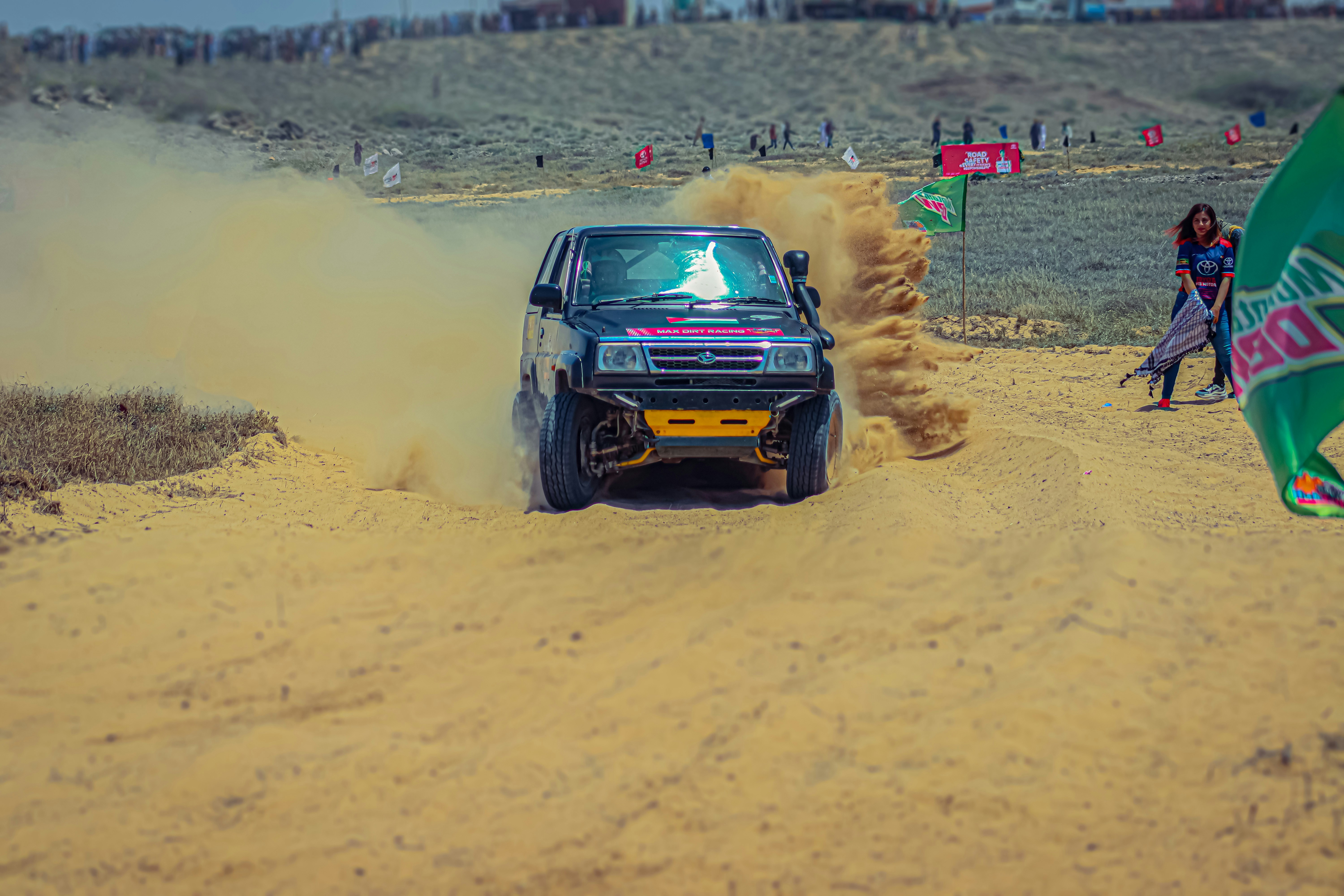 A truck driving down a dirt road next to a person