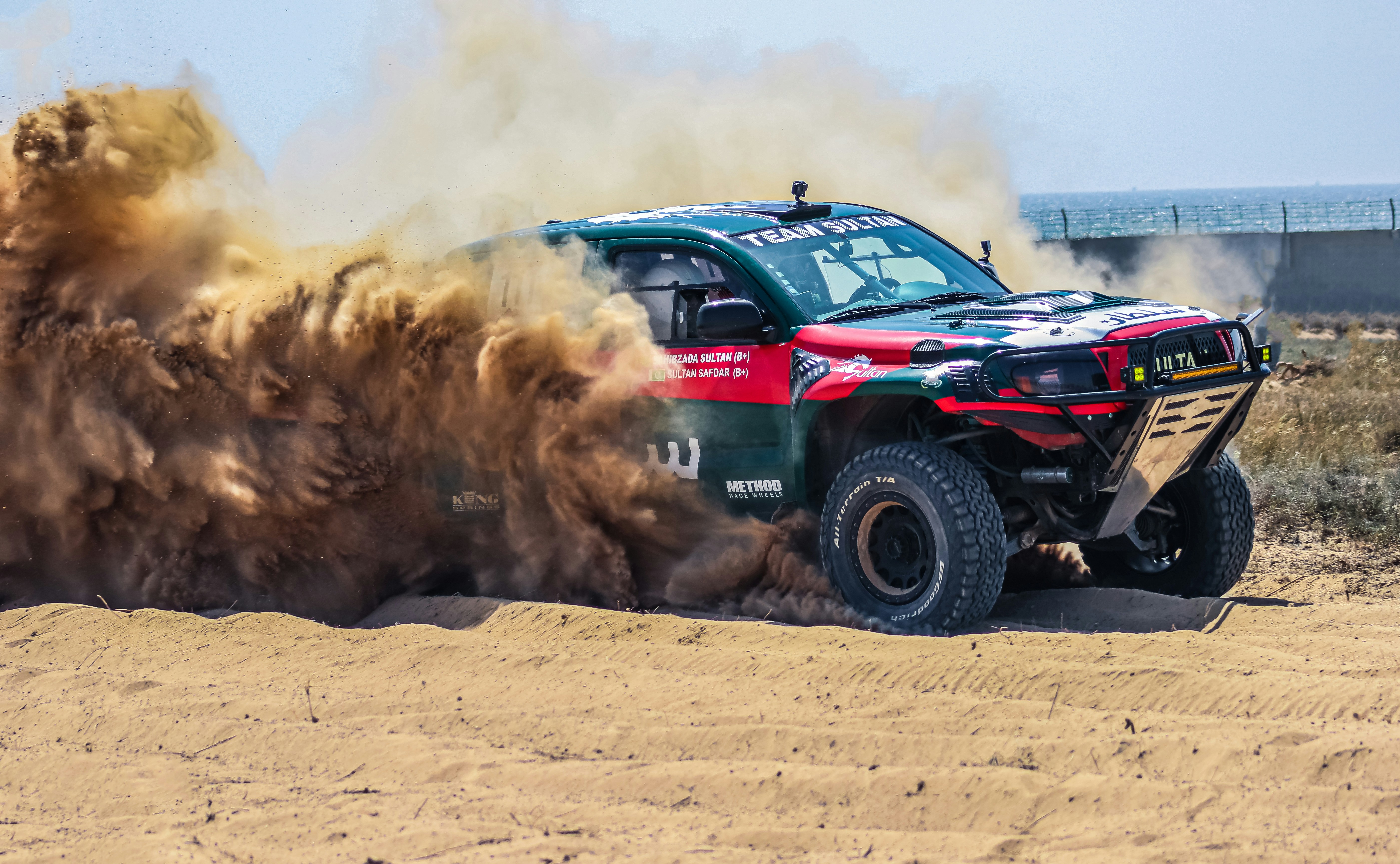 A monster truck kicking up dirt on a dirt road