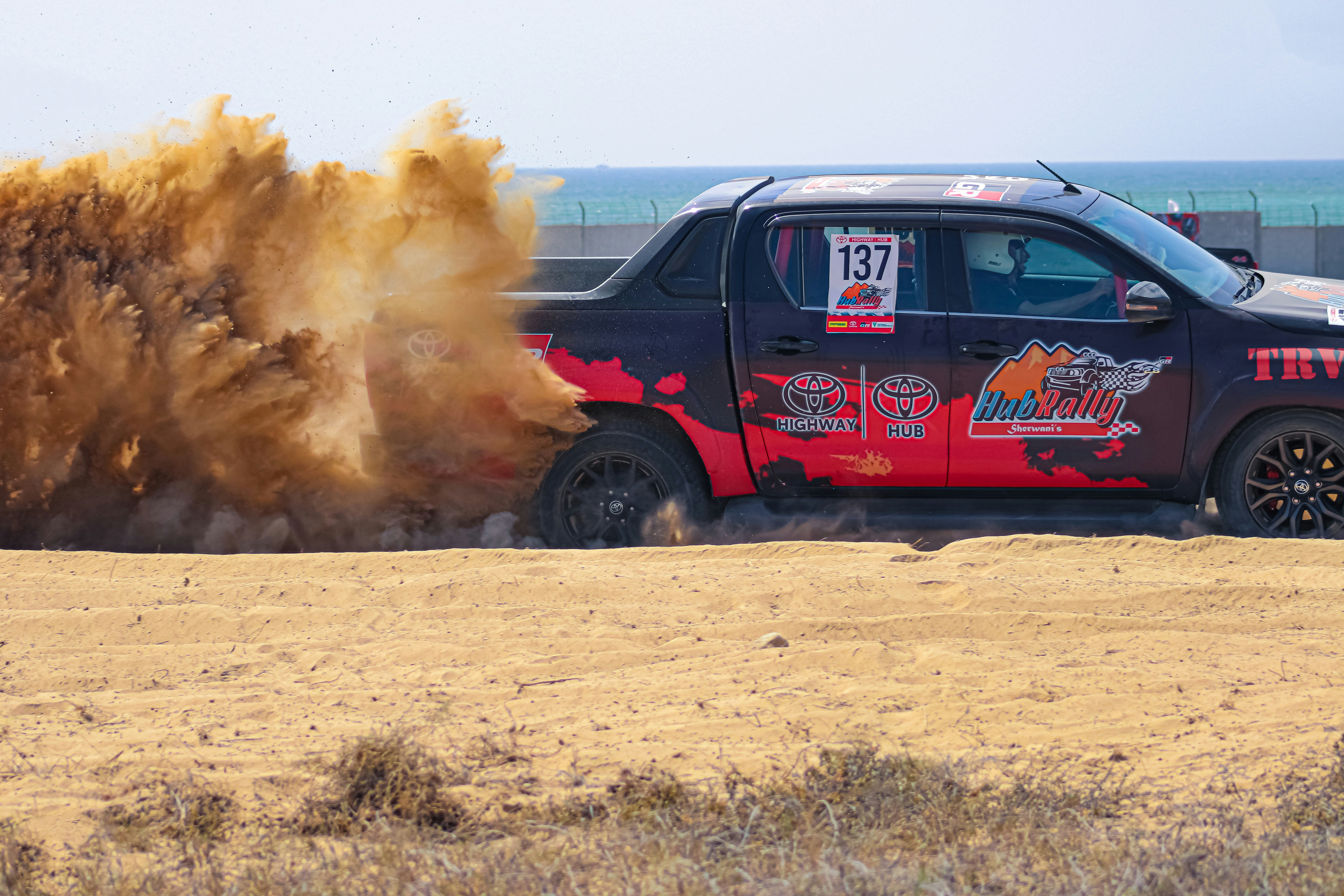 A car is kicking up dirt on the beach