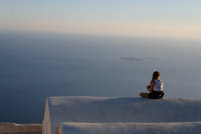 A person sitting on a ledge overlooking the ocean