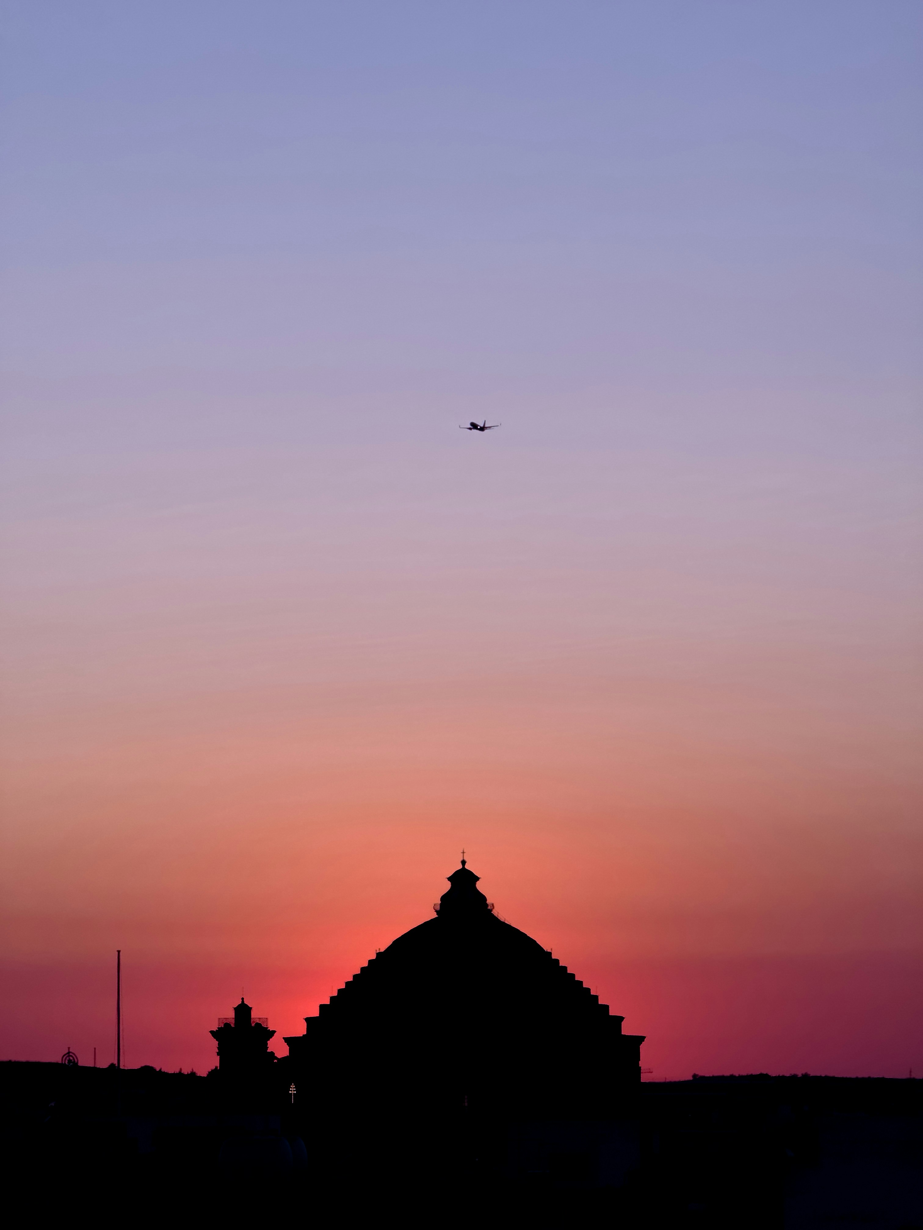 A plane is flying in the sky at sunset