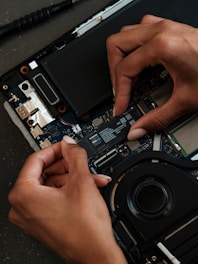 A person is removing the motherboard of a laptop