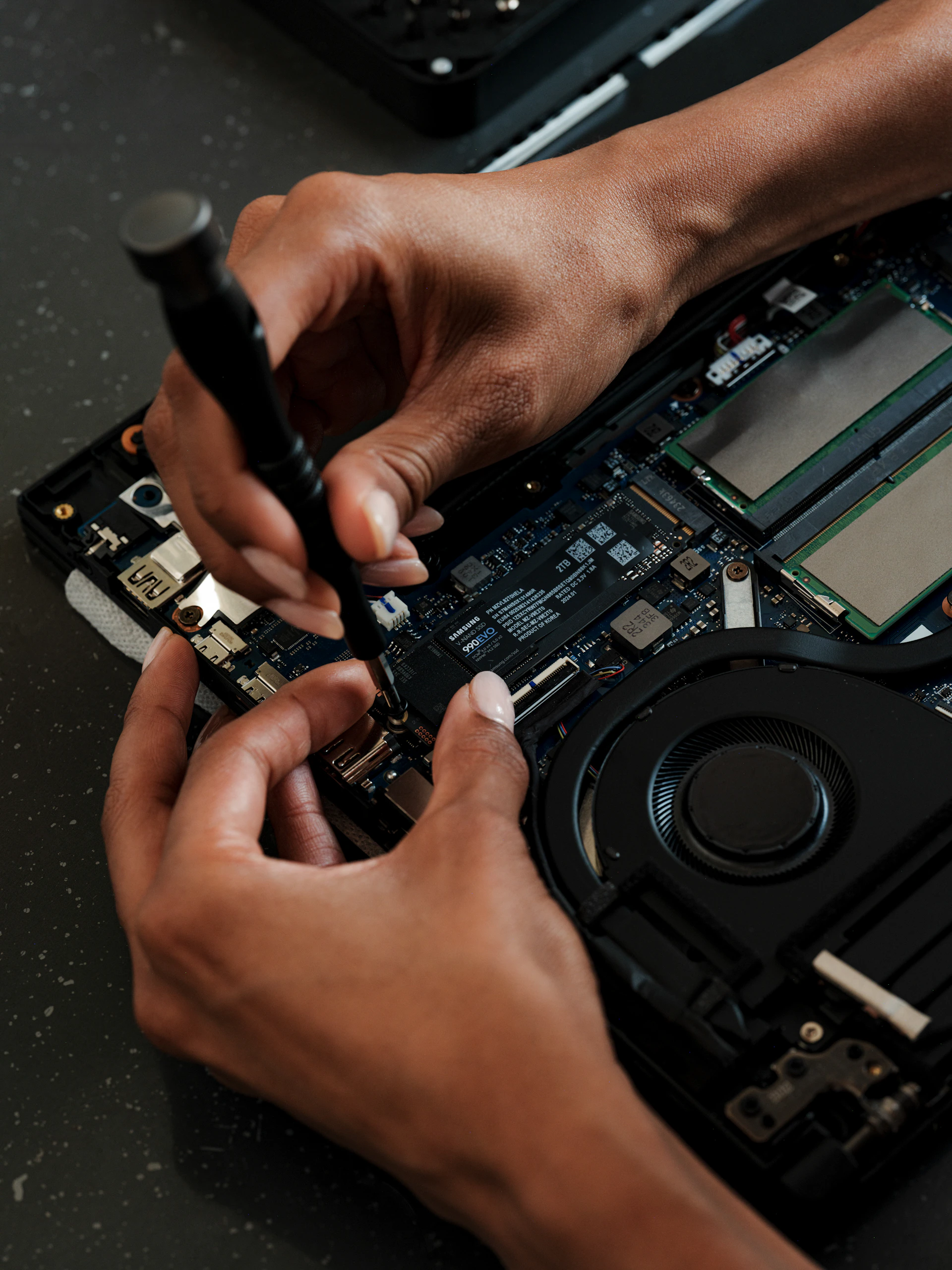 A person working on a laptop with a screwdriver