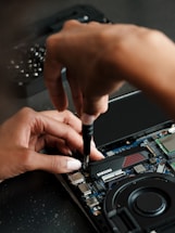 A person working on a laptop with a screwdriver