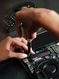 A person working on a laptop with a screwdriver