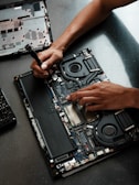 A person working on a laptop with a screwdriver
