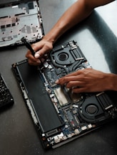 A person working on a laptop with a screwdriver