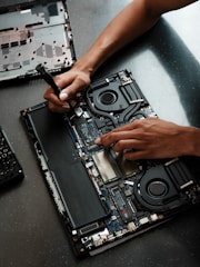 A person working on a laptop with a screwdriver