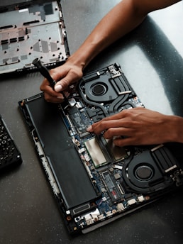 A person working on a laptop with a screwdriver
