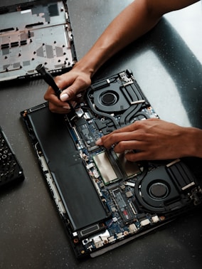 A person working on a laptop with a screwdriver