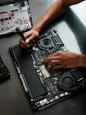 A person working on a laptop with a screwdriver