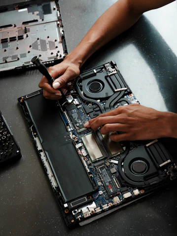 A person working on a laptop with a screwdriver