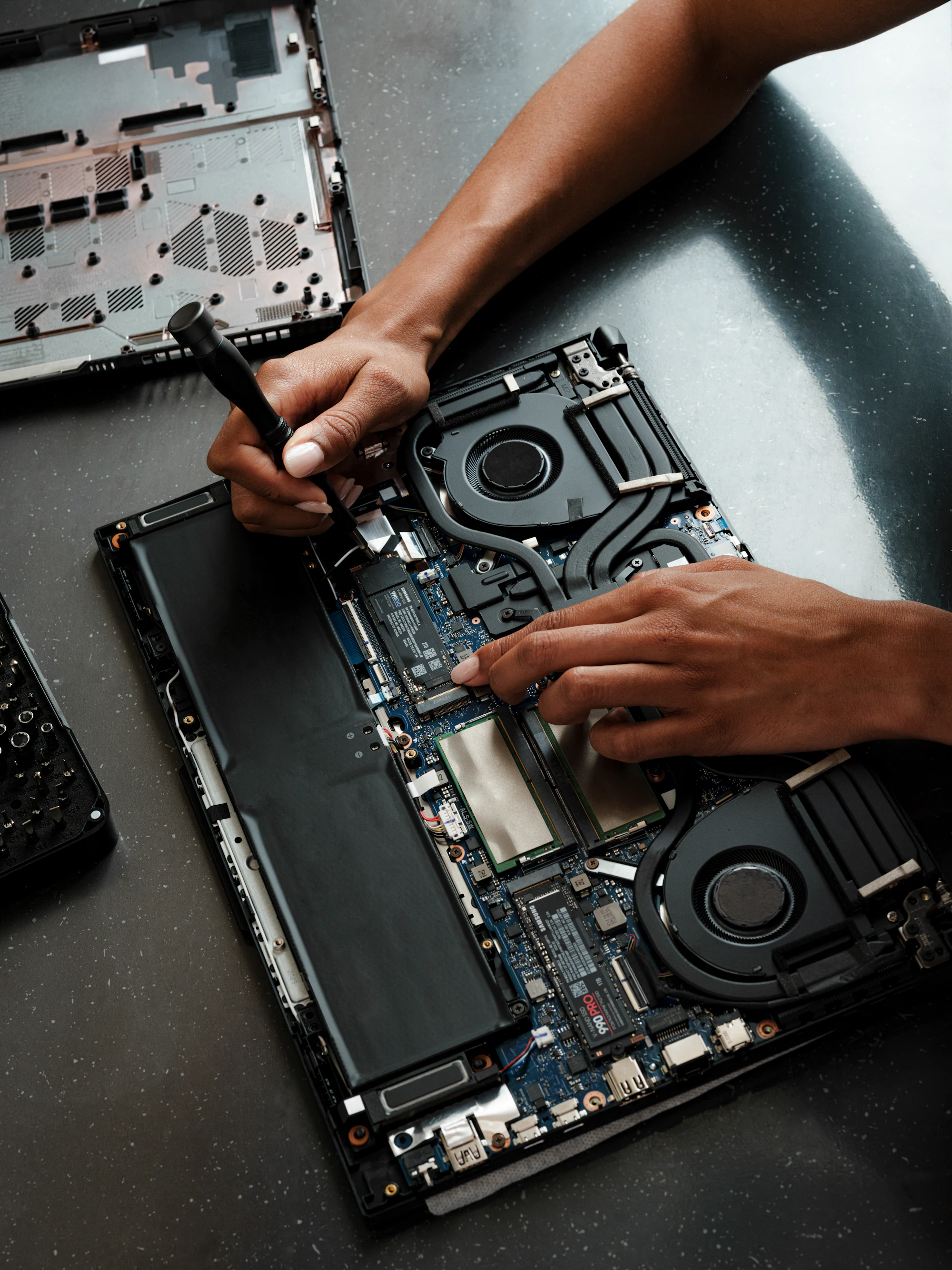 Technician working on an opened laptop with a screwdriver