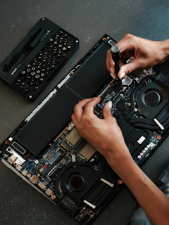 A man is working on a laptop with a screwdriver