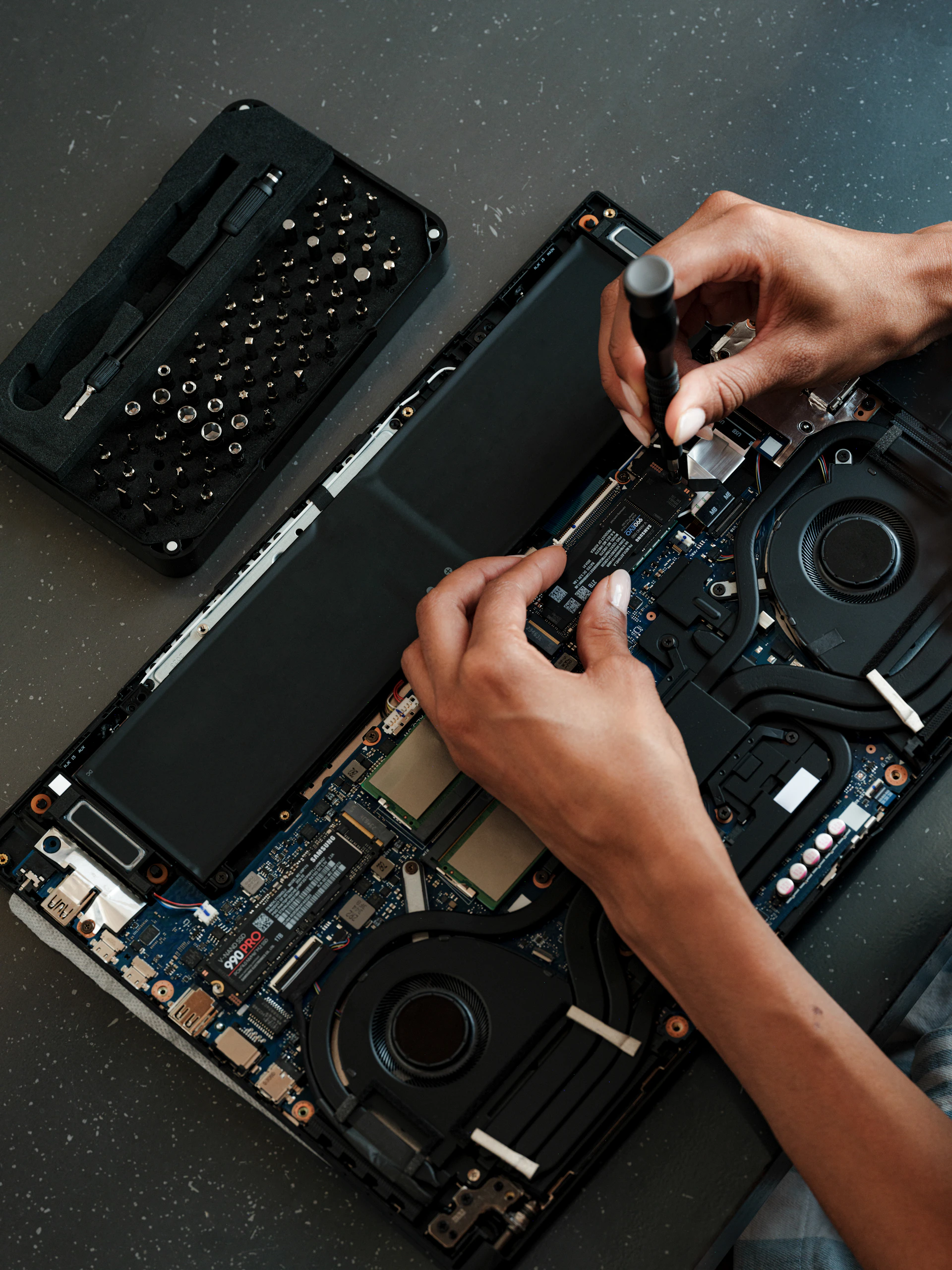 A man is working on a laptop with a screwdriver