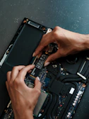 A person working on a laptop with a screwdriver
