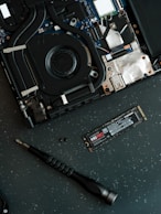 A hard drive being removed from the motherboard of a laptop